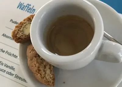 Eine Espresso-Tasse. Darunter liegt die gestaltete Speisekarte des Weekender Blankenese.